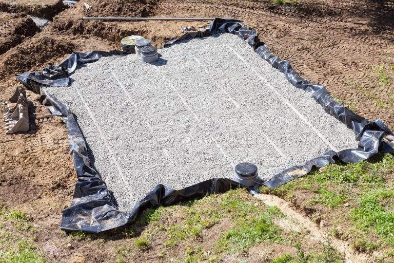 Aerial view of a new sand and gravel filter bed for a septic tank and wastewater disposal shwoing the layout of the filtration pipes, uncut plastic liner and filters and pump