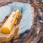 Worker installing a huge underground fuel tank, aerial
