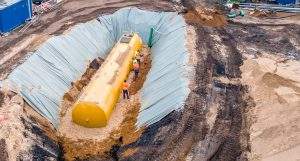 Worker installing a huge underground fuel tank, aerial