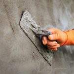 Plastering concrete to create industrial worker wall background with plastering tools