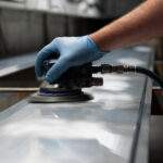 Man using orbital sander to prepare a metal panel