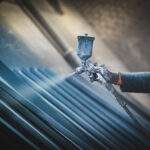 Man painting metal products with a spray gun