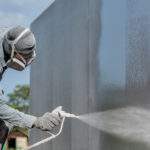 Airless Spray Painting, Worker painting on steel wall surface by airless spray gun for protection rust and corrosion.