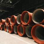 New cast and painted iron pipes for wastewater pipeline construction in warehouse storage.